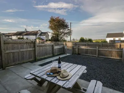 a picnic table with two hats and a bottle of wine at Edgemere Hideaway in Grange Over Sands