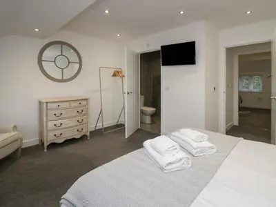 a white bedroom with a bed with two towels at Edgemere Hideaway in Grange Over Sands