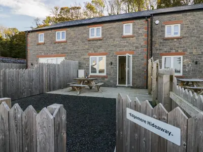 a brick house with a wooden fence in front of it at Edgemere Hideaway in Grange Over Sands