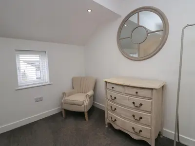 a bedroom with a dresser and a mirror and a chair at Edgemere Retreat in Grange Over Sands