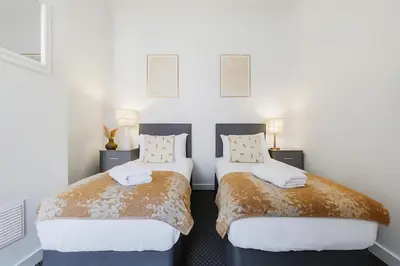 two beds in a room with white walls at Miranda House - Air Host & Stay - Sleeps 7 in Liverpool