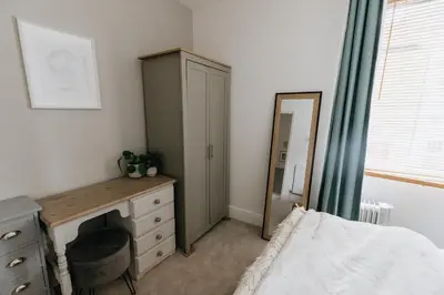 a bedroom with a bed and a dresser and a mirror at SUN COTTAGE - Cosy Cottage in Ulverston with a log burner in Ulverston, Cumbria in Ulverston