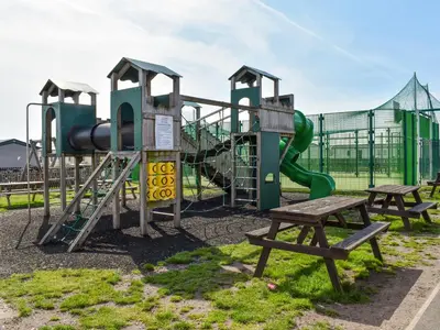 a playground with a slide and two benches at Edith Rose in Middleton