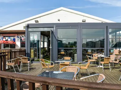 a patio with tables and chairs on a deck at Marni's Seaview in Heysham