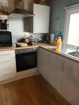 a kitchen with white cabinets and a black dishwasher at Fearless Fox Lodge in Altham
