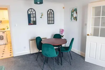a kitchen with a table and four green chairs at Kos apartment 5 in Liverpool