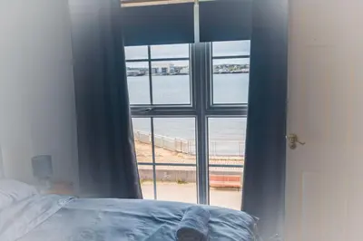 a bedroom with a window with a view of the ocean at Kos apartment 5 in Liverpool