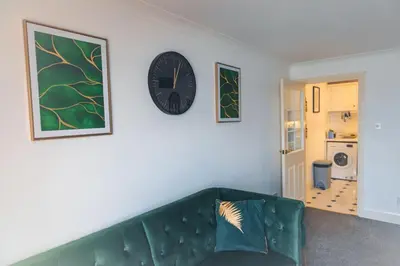 a green couch in a living room with a clock on a wall at Kos apartment 5 in Liverpool