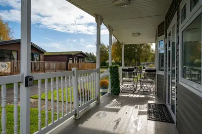 a porch with a white fence and a table at Peaceful 3-Bed Lodge ! Ideal for Families! in Warton