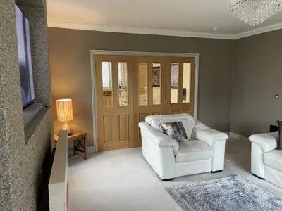 a living room with a white chair and a television at Priory Gardens – Birkdale - 2 bed in Southport