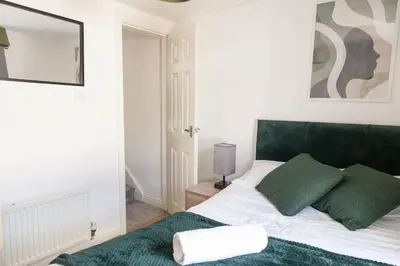 a bedroom with a bed with green and white pillows at Modern 5-Bedroom House with 8 Beds, Perfect for Contractors, Extended Stay Savings in Wallasey
