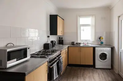 a kitchen with a microwave and a stove top oven at Modern 5-Bedroom House with 8 Beds, Perfect for Contractors, Extended Stay Savings in Wallasey