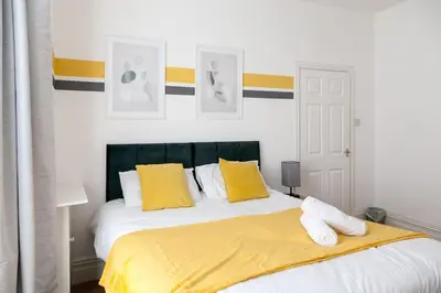 a bedroom with a bed with yellow and white pillows at Modern 5-Bedroom House with 8 Beds, Perfect for Contractors, Extended Stay Savings in Wallasey