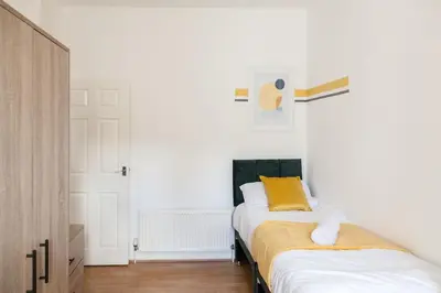 two beds in a room with white walls and yellow pillows at Modern 5-Bedroom House with 8 Beds, Perfect for Contractors, Extended Stay Savings in Wallasey
