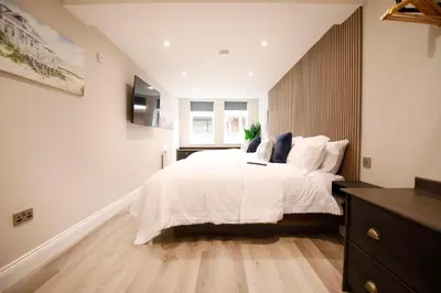 a bedroom with a large bed with white sheets and blue pillows at Oceania Suites in Blackpool