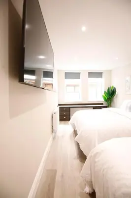two beds in a bedroom with white walls at Oceania Suites in Blackpool