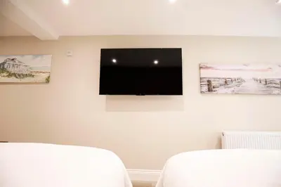 a bedroom with two beds and a flat screen tv on the wall at Oceania Suites in Blackpool