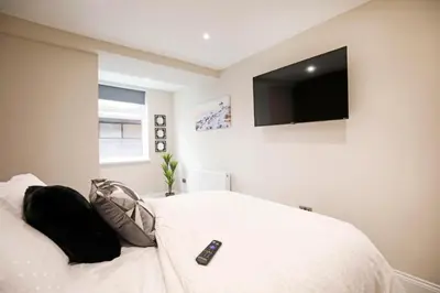 a bedroom with a bed with a tv on the wall at Oceania Suites in Blackpool
