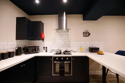 a kitchen with black cabinets and white counter tops at Oceania Suites in Blackpool