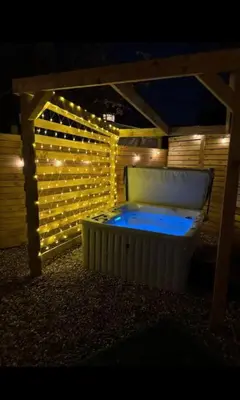 a jacuzzi tub in a backyard with lights at GGs Holiday Let in Poulton le Fylde
