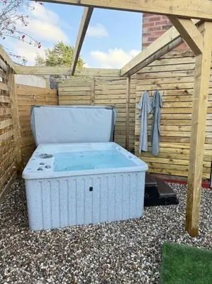 a hot tub sitting next to a wooden fence at GGs Holiday Let in Poulton le Fylde