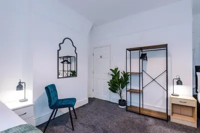 a bedroom with a blue chair and a mirror at St Paul's by YourStays - 1 Bedroom House in Merseyside in Seacombe