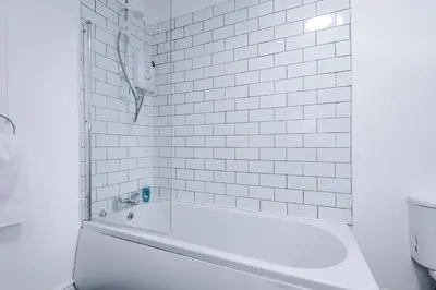 a white tiled bathroom with a bath tub at St Paul's by YourStays - 1 Bedroom House in Merseyside in Seacombe