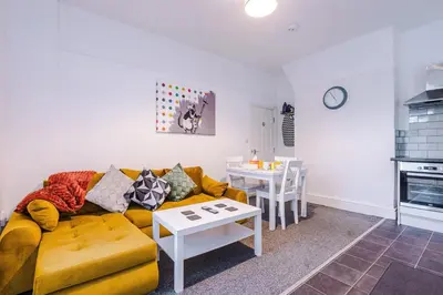 a living room with a yellow couch and a table at St Paul's by YourStays - 1 Bedroom House in Merseyside in Seacombe