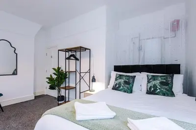 a bedroom with a bed with white sheets and green pillows at St Paul's by YourStays - 1 Bedroom House in Merseyside in Seacombe