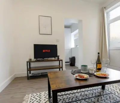 a living room with a table and a tv at Beautiful & Spacious Suite in Blackpool Centre in Blackpool