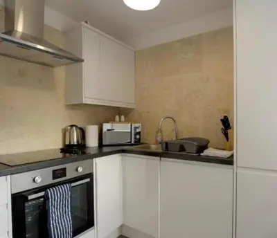 a kitchen with white cabinets and a stove top oven at Beautiful & Spacious Suite in Blackpool Centre in Blackpool