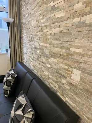 a black couch in front of a brick wall at Beautiful & Spacious Suite in Blackpool Centre in Blackpool