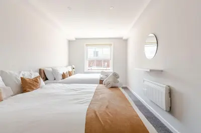 a large white bedroom with a teddy bear sitting on the floor at Large 2-Bedroom Apartment, Liverpool City Centre - Sleeps up to 10 in Liverpool