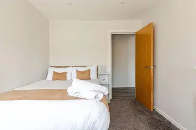a bedroom with a bed with white sheets and orange pillows at Large 2-Bedroom Apartment, Liverpool City Centre - Sleeps up to 10 in Liverpool