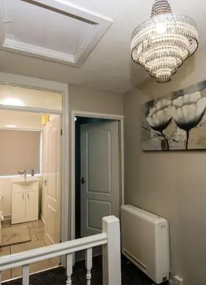 a room with a chandelier and a hallway with a staircase at Swindon Dream in Liverpool