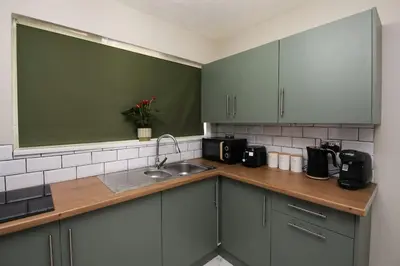 a kitchen with green cabinets and a sink at Swindon Dream in Liverpool