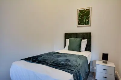 a bedroom with a bed with white sheets and green pillows at Wigan - Apartment - Sleeps 3 - Parking - Stadium in Wigan