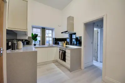 a kitchen with white cabinets and a stove top oven at Wigan - Apartment - Sleeps 3 - Parking - Stadium in Wigan