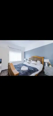 a bedroom with a king sized bed and a chair at Walton Residence in Liverpool