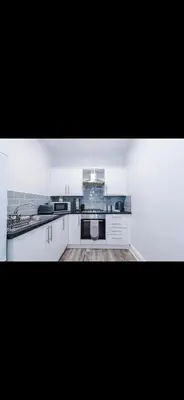 a kitchen with white cabinets and a stove top oven at Walton Residence in Liverpool