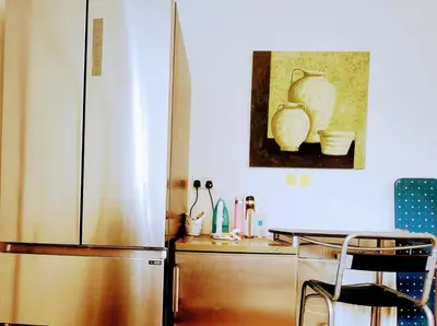 a kitchen with a refrigerator and a table with a chair at Luxury King-size Rm in Bolton