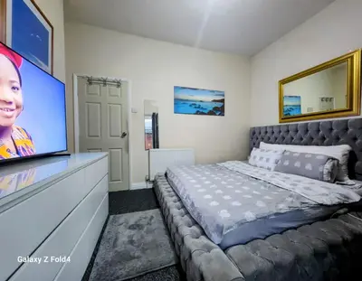 a bedroom with a large bed and a tv at Luxury King-size Rm in Bolton