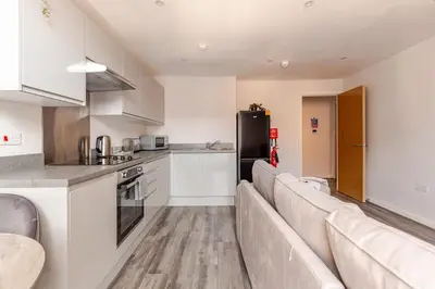 a kitchen with white cabinets and a couch in a room at Spacious 2Bed Central Liverpool Nightlife & Events, sleeps up to 10 in Liverpool