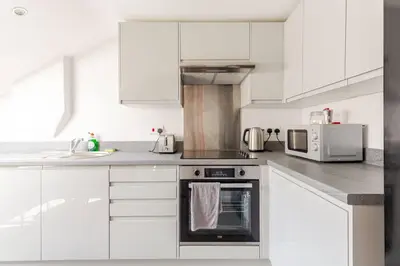 a white kitchen with a stove and a microwave at 2-Bed Apartment with Sofa Bed, Sleeps up to 6, Perfect for Groups & Familie in Liverpool