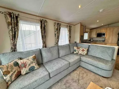 a living room with a blue couch and a kitchen at Glenmoor Lodge in Clitheroe