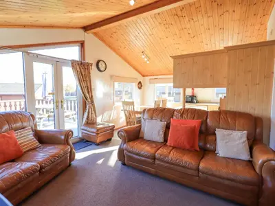 a living room with brown leather couches and a kitchen at Kellet Lodge Lakeside 26 in Carnforth