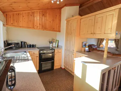 a kitchen with wooden cabinets and a black stove at Kellet Lodge Lakeside 26 in Carnforth