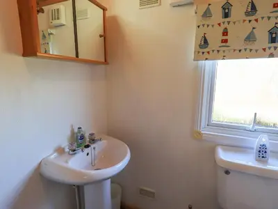 a bathroom with a sink and a toilet and a window at Kellet Lodge Lakeside 26 in Carnforth