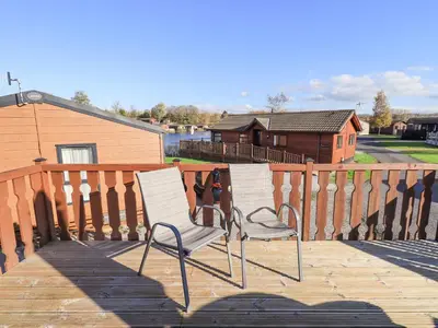 two white chairs sitting on a wooden deck at Kellet Lodge Lakeside 26 in Carnforth
