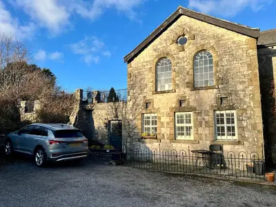 a car parked in front of a stone house at 1 Boarbank Farm in Grange Over Sands